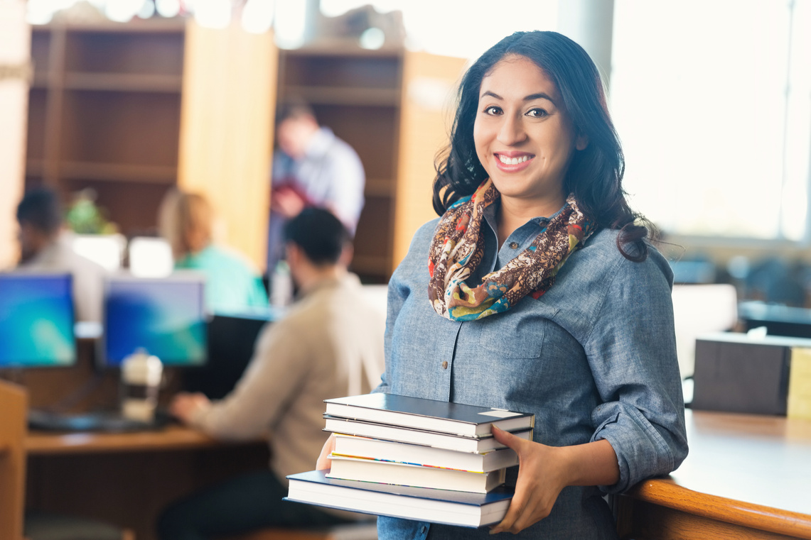 Young adult college student borrowing books from library